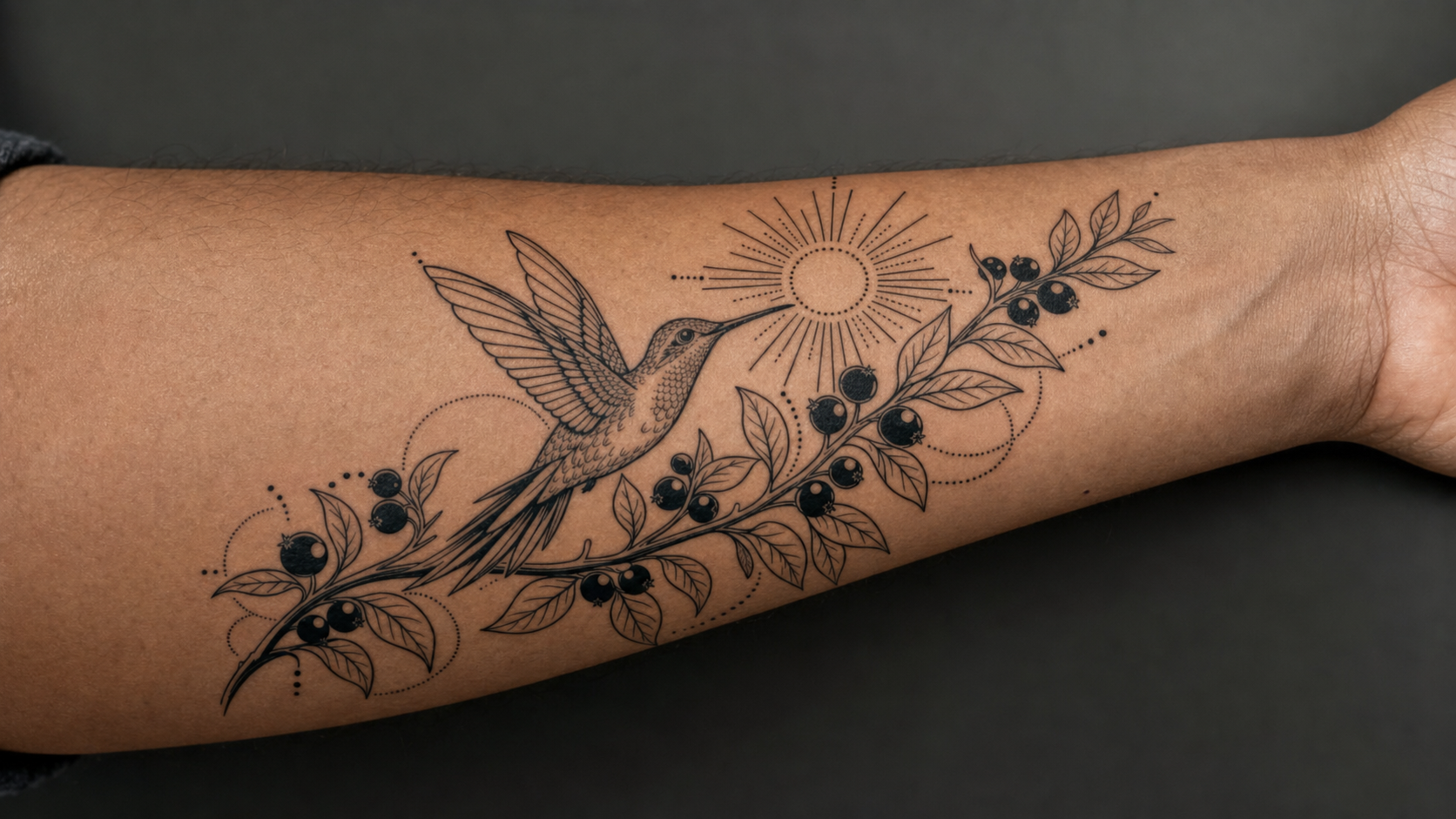 Tatuagem autoral de beija-flor e jabuticaba aplicada e alinhada ao antebraço